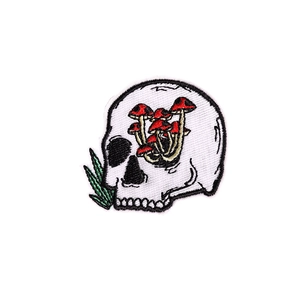 Punk style skull embroidery patch with red mushrooms and green leaves on white background