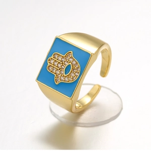 Golden ring with blue enamel and Fatima hand zircon pattern on a white background