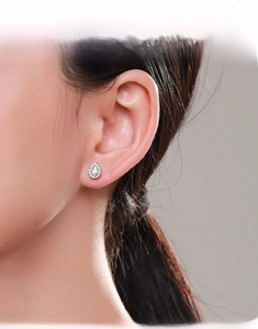 Model wearing silver pear-shaped halo stud earrings with sparkling crystals