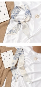 Detail of silk narrow scarf featuring blue balloon patterns tied in a bow on fabric