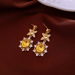 Macro view of gold-plated star horse earring with yellow oval gemstone on red silk