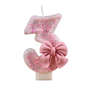 Pink glitter number 3 birthday candle with a decorative bow on a white background