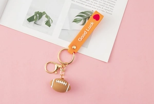 Detail of rugby keychain with brown ball pendant and orange Good Luck lanyard