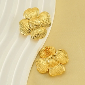 Close-up of golden metal flower earrings featuring detailed textures and a polished finish