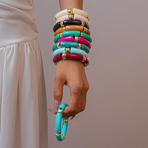 Dettaglio di set bracciali in acrilico stile bambù con distanziali dorati metallici