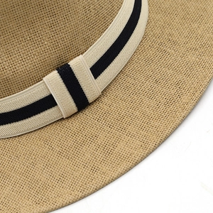 Detailed close-up of woven paper straw texture and black striped ribbon on the sun hat