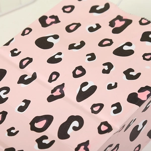 Close-up of pink leopard heart pattern on kraft paper party gift bag surface