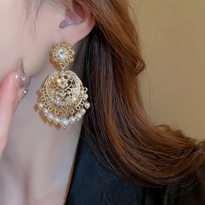 Close-up of vintage gold earrings with hollow carving, rhinestones and pearl tassels