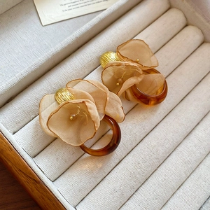 Macro detail of champagne chiffon flower earrings with amber resin ring and gold accents