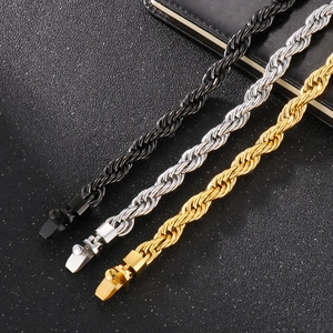 Dettaglio di bracciali a catena intrecciata spessi in nero, argento e oro in acciaio inox