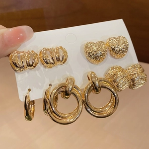 Close-up of four pairs of high-gloss gold geometric earrings on a white display card