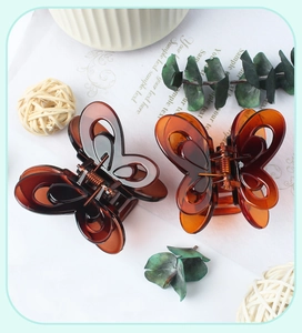 Macro detail of amber butterfly hair claw clips on decorative paper with leaves