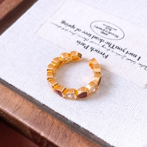 Macro view of gold-plated heart ring featuring red enamel and sparkling white zircons
