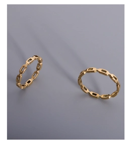 Close-up of dual stackable golden geometric link rings in minimalist polished titanium steel