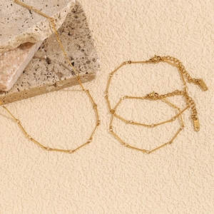 Flat lay of 18K gold plated stainless steel necklace and bracelet set on stone decor