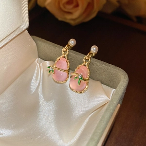 Macro shot of pink resin gourd earrings with pearl accents and golden leaf details