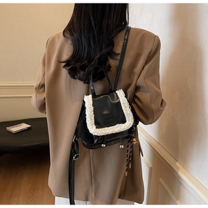 Rear view of model wearing a black mini bucket backpack with white faux shearling trim