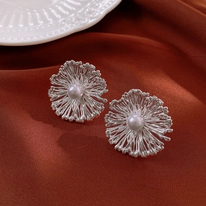 Detailansicht floraler Silber-Ohrstecker mit Perle auf dunkelrotem Seidenhintergrund