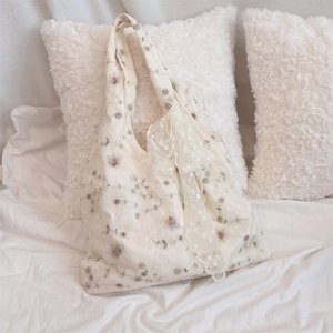 Detailed embroidery on tulle mesh of a cream shoulder bag with lace bow decoration