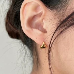 Close-up of minimalist gold triangular geometric stud earrings worn by a model