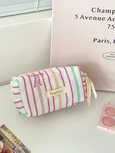 Quilted striped makeup bag with pink bow pattern and ribbon zipper shown in flat lay