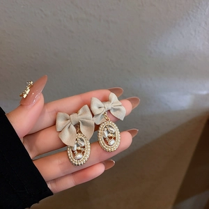 Close-up of elegant fabric bow earrings with pearl and rhinestone details in gold frame