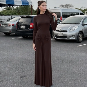 Detail of elegant slim-fit long-sleeved brown dress with ruched waist and floor-length hem