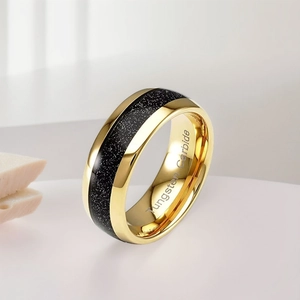 Macro view of gold tungsten ring with black glitter inlay and interior engraving