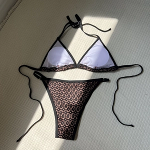 Detail of two-piece bikini featuring black crochet lace over pink fabric with side ties