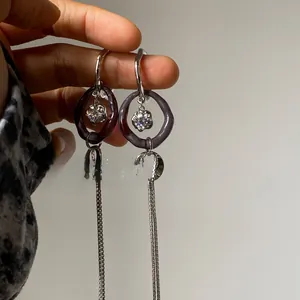 Detailed macro view of long silver tassel earrings with purple resin hoops and zircons