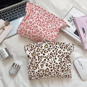 Corduroy leopard print makeup bags shown with tech and beauty accessories on white fabric