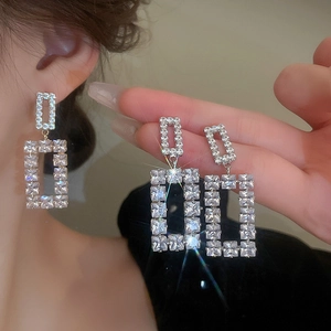 Macro detail of geometric silver earrings with sparkling rectangular zircon inlay for women