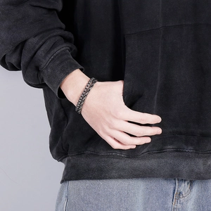 Detail of gunmetal dual-layer stainless steel chain bracelet on male wrist in street style