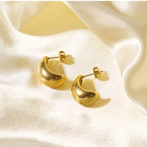 Polished 18k gold plated teardrop earrings placed on elegant white silk fabric