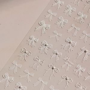 3D white bow nail art stickers with embossed texture and pearl accents for manicure