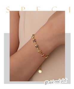 Detailed shot of a gold butterfly bracelet featuring colorful acrylic charms on a female wrist