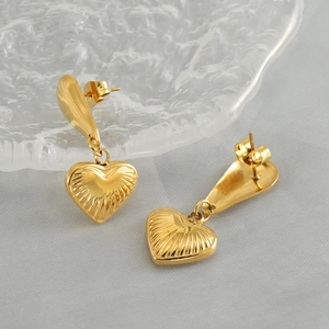 Golden heart-shaped stainless steel drop earrings featuring textured radial relief patterns