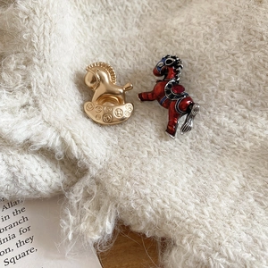 Vue détaillée des broches cheval émaillées sur un fond en tricot blanc élégant