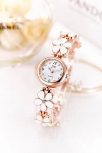 Macro shot of rose gold quartz watch featuring white floral links and crystal accents