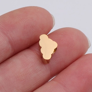 Macro-opname van een kleine gouden wolkvormige kraal tussen de vingertoppen