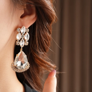 Close-up of vintage golden rhinestone drop earring with crystal flower details on model