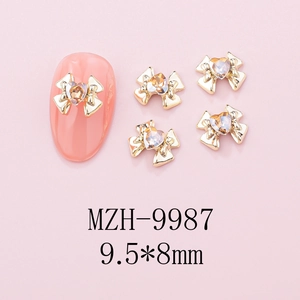 Macro shot of 9.5x8mm gold alloy bow nail charms with heart rhinestone on pink nails