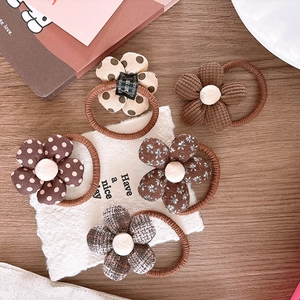Detailed flat lay of five floral brown elastic hair ties on a rustic wooden table background