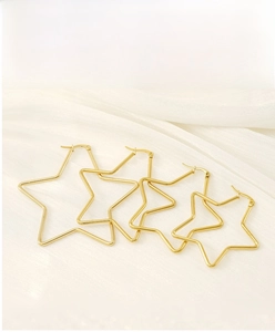 Detailed set of four graduated gold star-shaped stainless steel hoop earrings on white silk