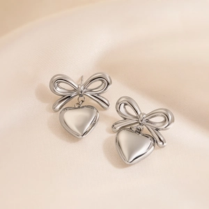 Silver bow heart earrings in polished stainless steel on champagne silk background