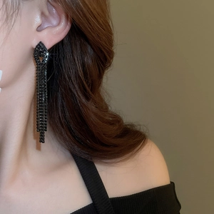 Detail of long black tassel earrings with sparkling crystals worn by a model
