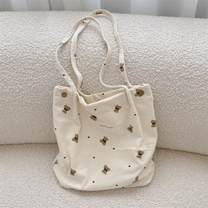 Detail of beige corduroy tote bag showing cartoon bear patterns and textured fabric finish