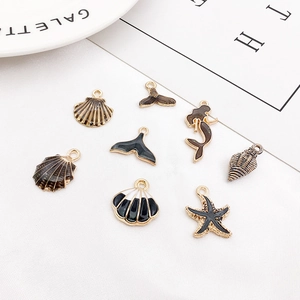 Detail of nautical enamel charms featuring shell, whale tail, and starfish in black and gold