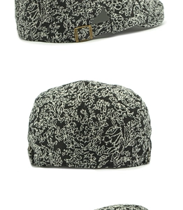 Detail of vintage jacquard newsboy cap with black and white floral pattern and metal buckle