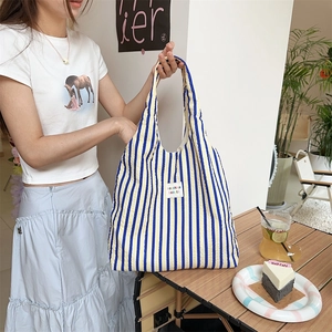 Detail of yellow and blue seersucker striped tote bag shown in a lifestyle cafe setting